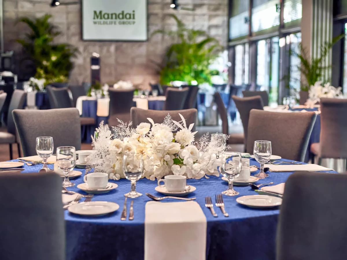 Elegant dining table setup with floral centerpiece in modern event space.