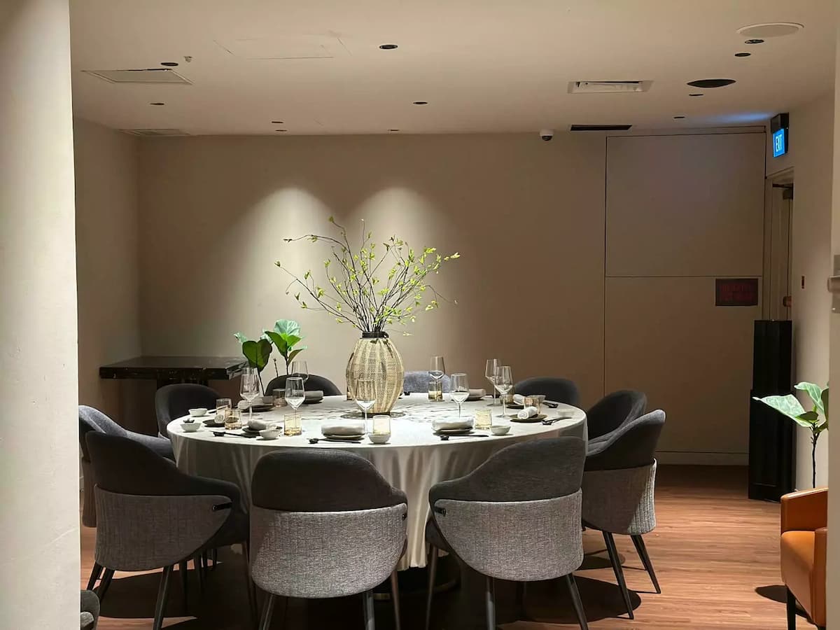 an elegant restaurant table setting features crystal wine glasses, rolled white linens, and dark ceramic plates on a polished black surface.