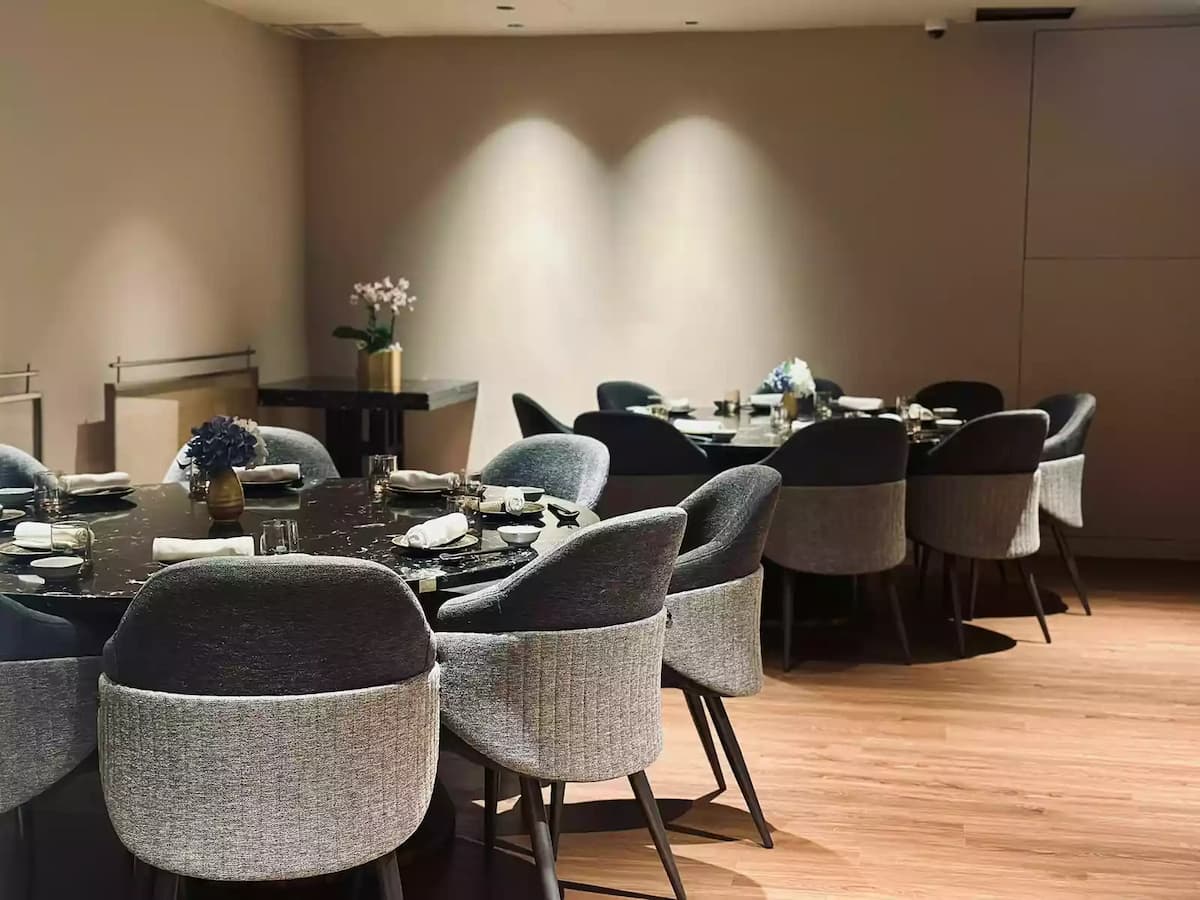 room featuring round black marble tables and curved, textured grey upholstered chairs on a light wood floor