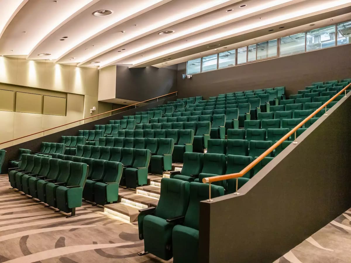Tiered auditorium seating with green chairs and modern interior.