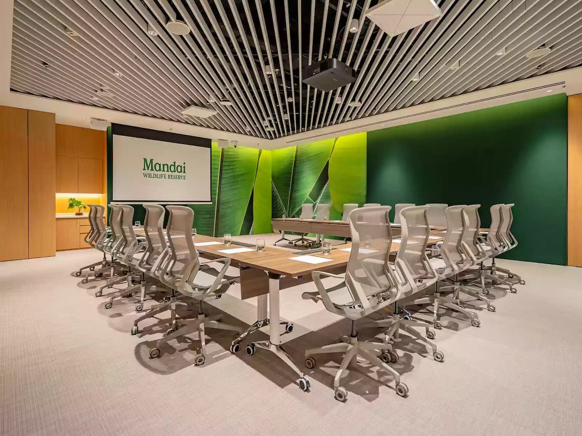 Modern boardroom with conference tables, ergonomic chairs, and presentation screen.