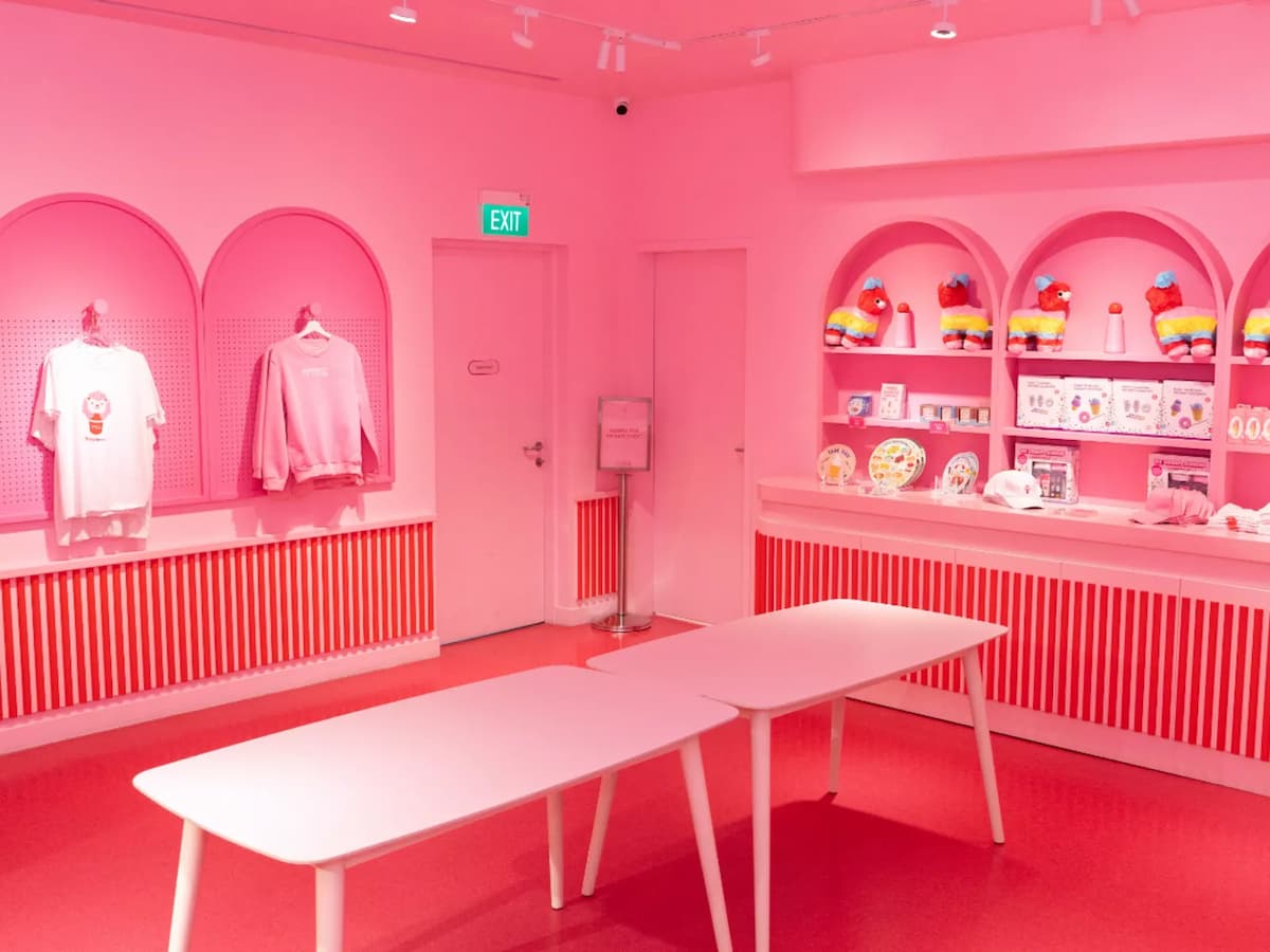 Pink-themed retail interior with arched displays, merchandise on shelves, and white tables in the foreground.