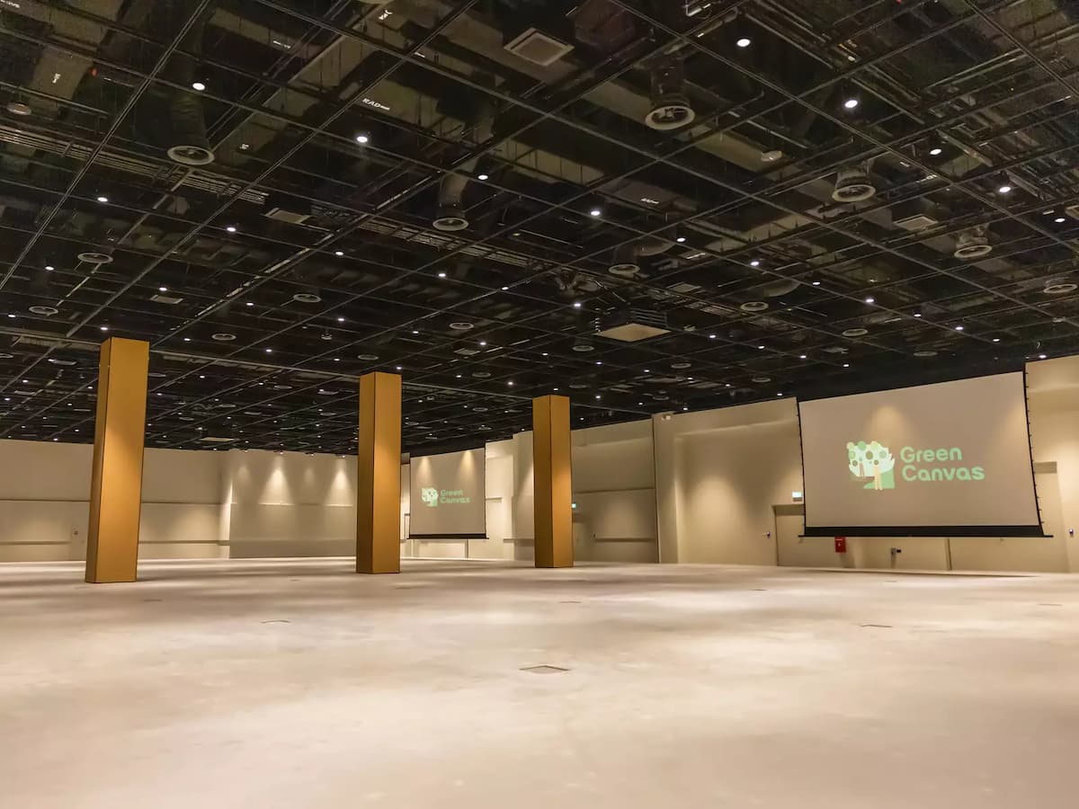 Expansive convention hall with high ceiling, pillars, and projection screens.