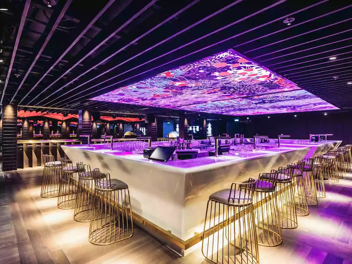 Modern bar with illuminated counters and vibrant purple LED ceiling.