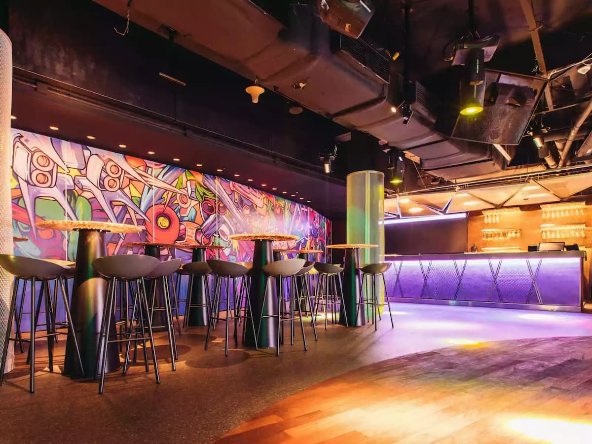 Modern bar area with high tables, mural wall, and ambient lighting.