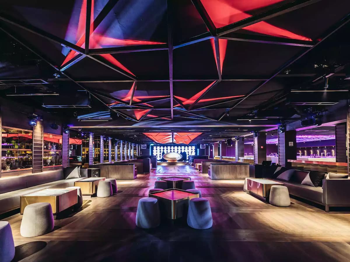 Modern lounge with geometric LED ceiling, plush seating, and dramatic ambient lighting.