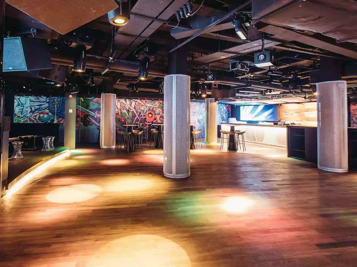 Spacious nightclub-style venue with dance floor, bar, and ambient lighting.