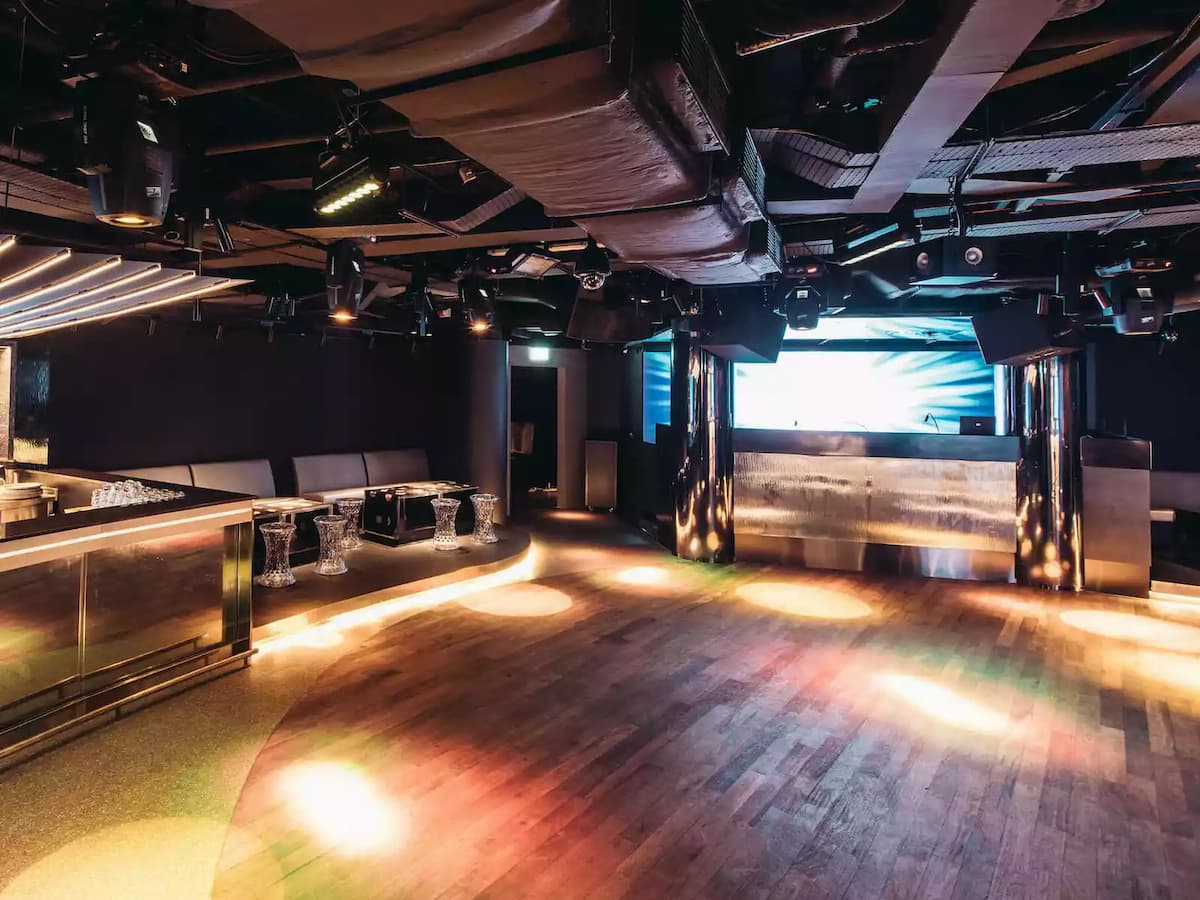 Nightclub-style event space with stage, LED screen, and ambient lighting.