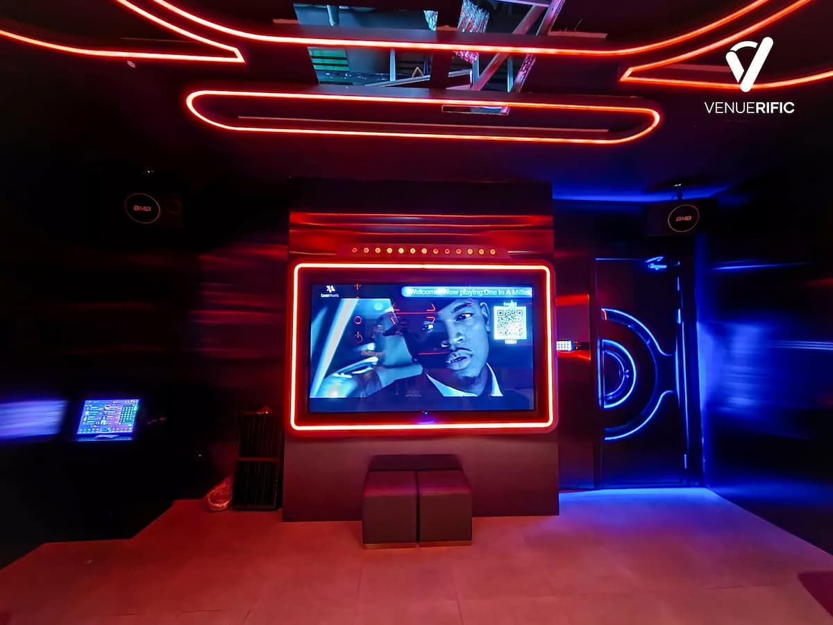 Entertainment room featuring a large screen framed in red neon and a futuristic blue-lit door.