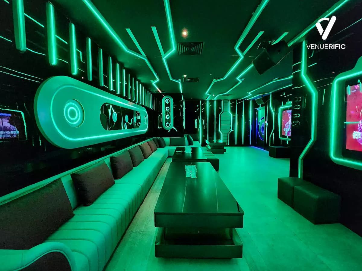 Green-lit futuristic lounge with long sofas and geometric neon wall patterns.