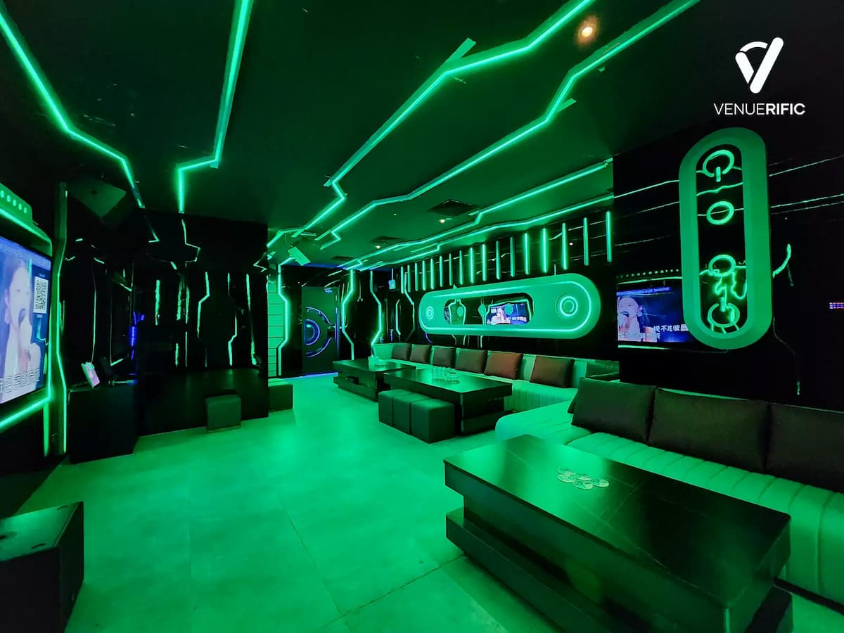 Green-lit futuristic lounge with long sofas and geometric neon wall patterns.