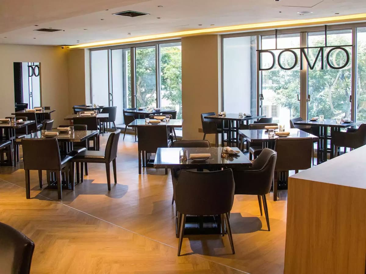 Modern restaurant dining area with square tables and large windows.