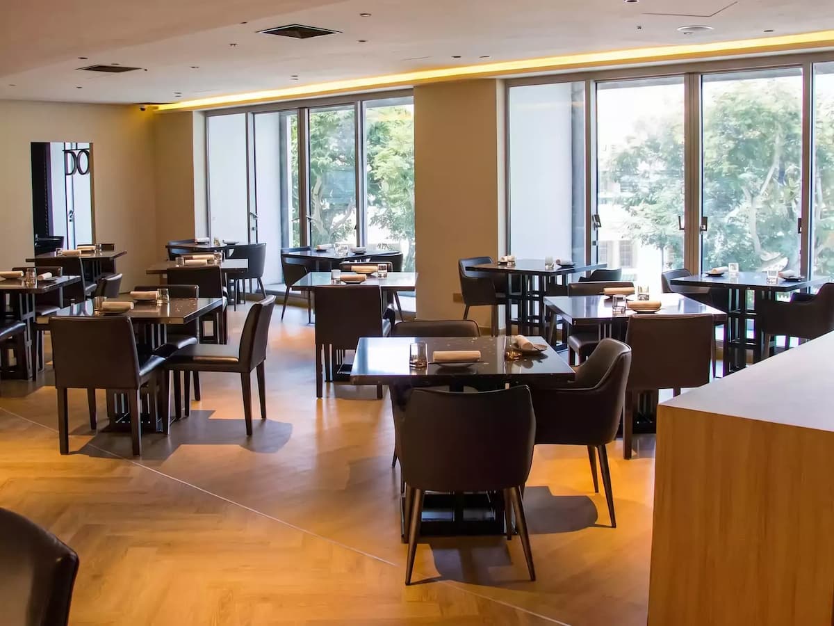 Modern restaurant dining area with square tables and large windows.