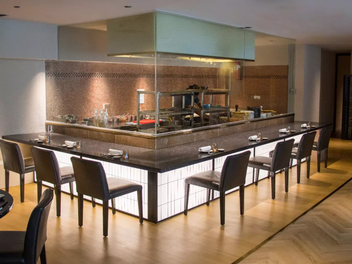 Modern restaurant with open kitchen counter and bar seating.