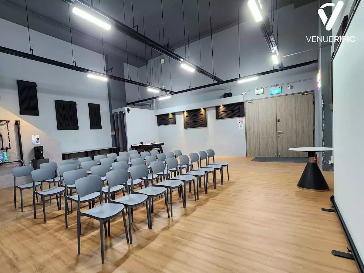 Modern classroom-style event room with rows of chairs, wood flooring, and an open industrial ceiling.
