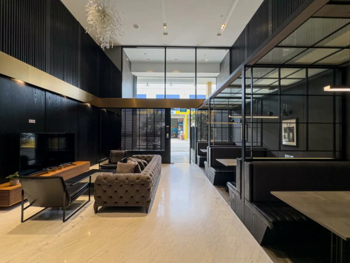 A wide, bright view of a modern lounge area showing the transition between open sofa seating and private dining booths.
