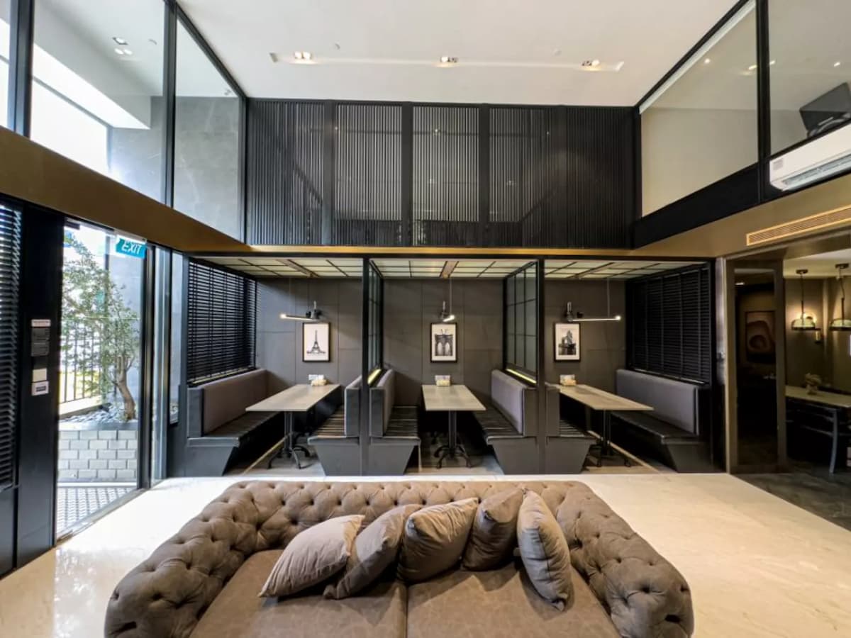 A centered view of a luxury lounge with a tufted sofa, a large television on a wood console, and a gold-trimmed mezzanine above.
