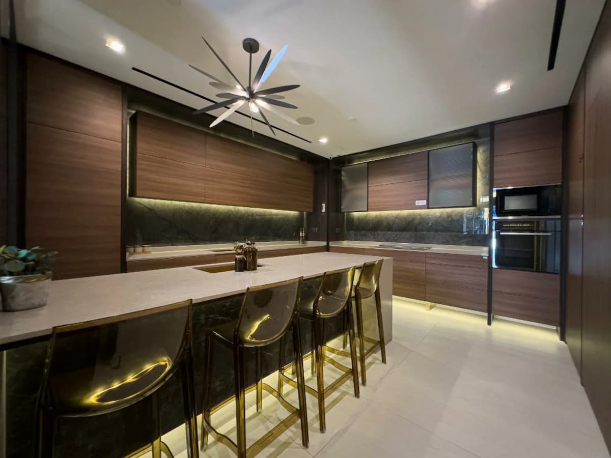 A modern, private dining space featuring a sleek marble table, black contemporary chairs, and a warm, chevron-patterned wood feature wall.