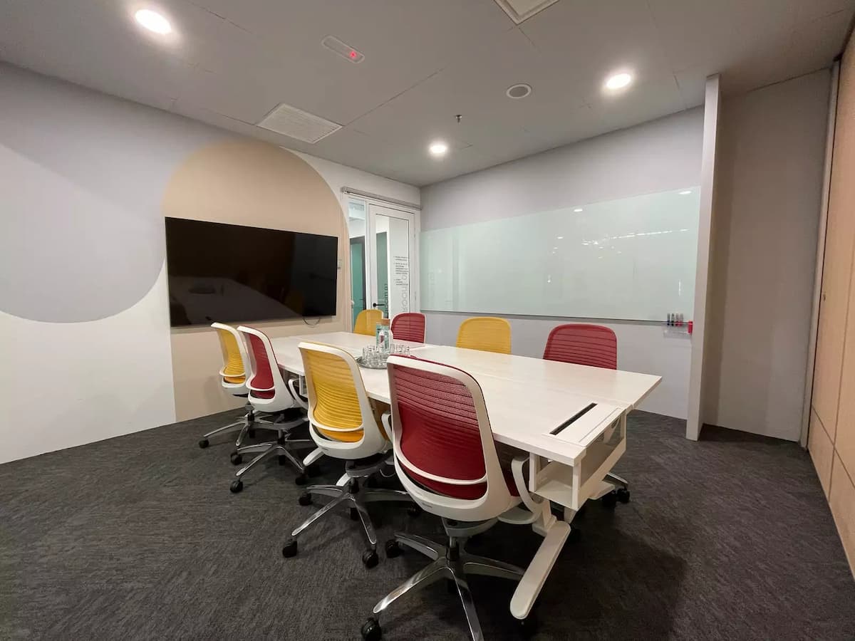 Modern meeting room with white conference table, red and yellow chairs