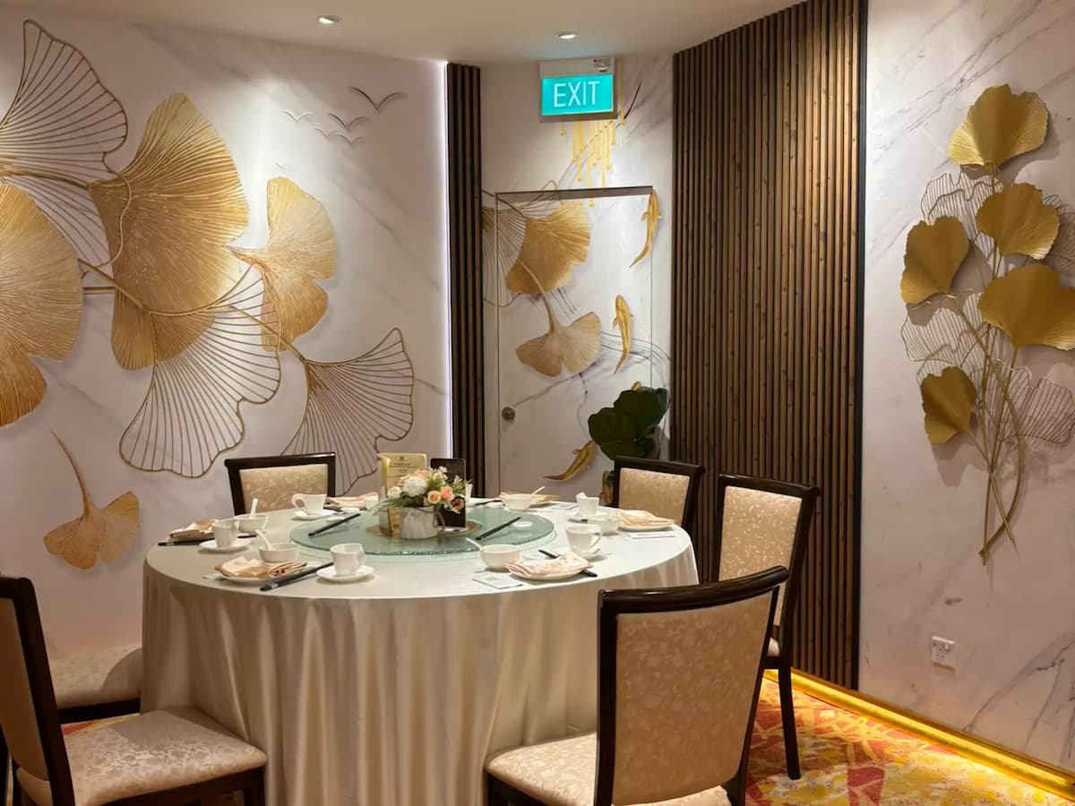 Intimate private dining room with a round table, refined place settings, and gold botanical wall art accents.