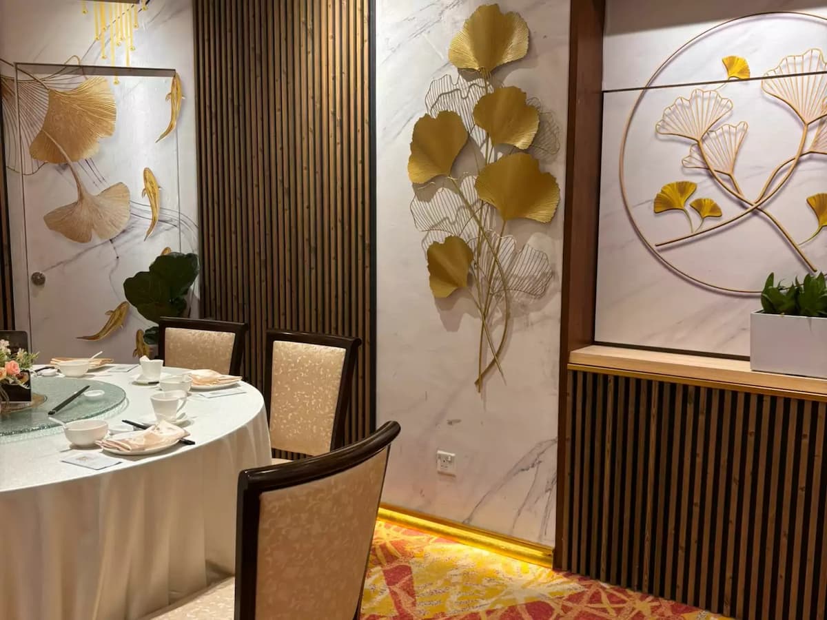 Intimate private dining area with round table, upholstered chairs, and elegant gold leaf wall art accents.