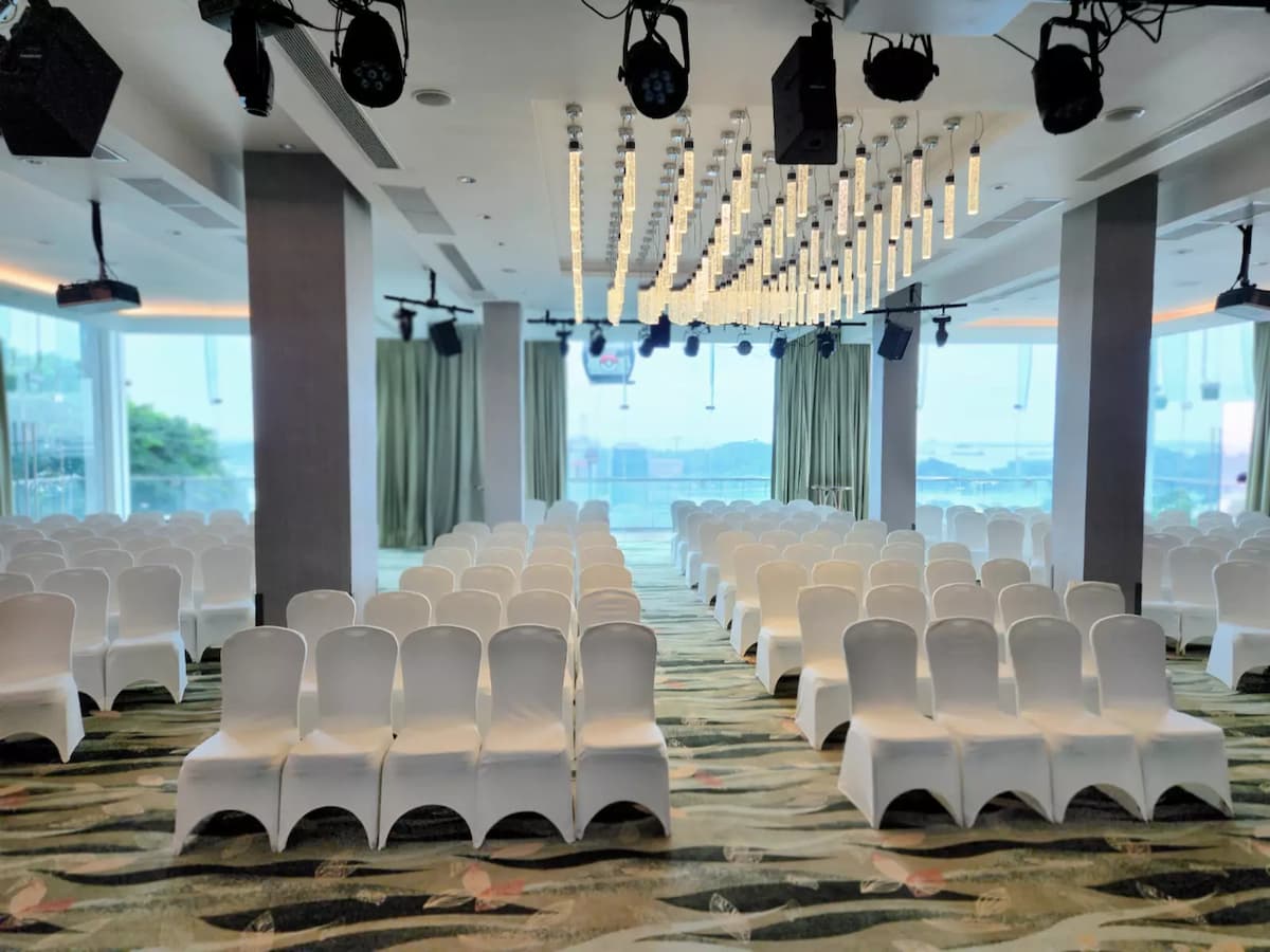 Modern event hall with rows of white chairs set theatre-style under contemporary ceiling lights.