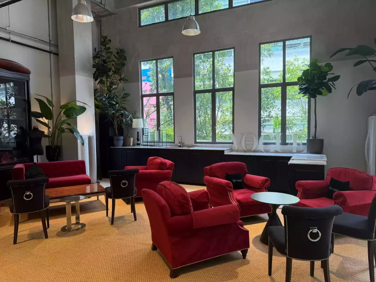Elegant lounge area with red armchairs and large windows.