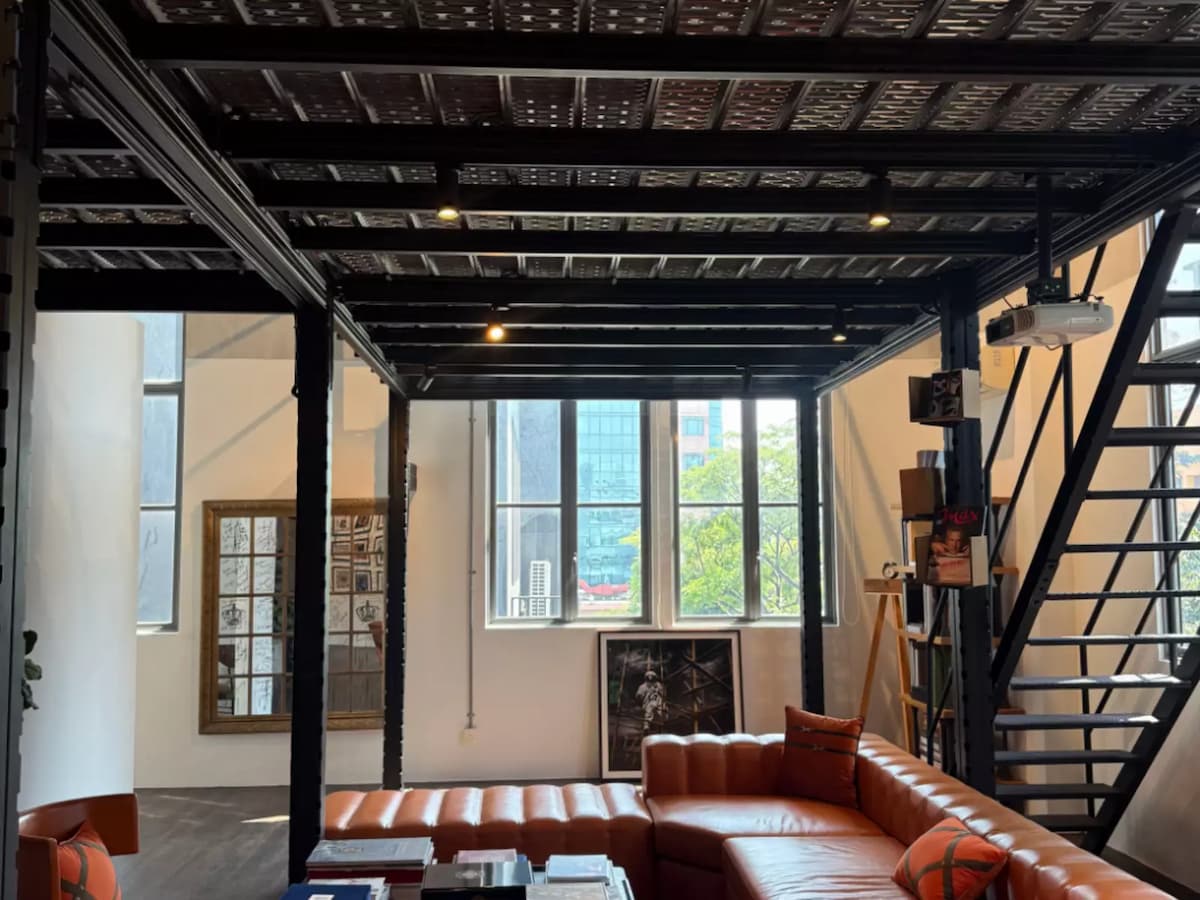 Industrial loft lounge with leather sofa, mezzanine, and staircase