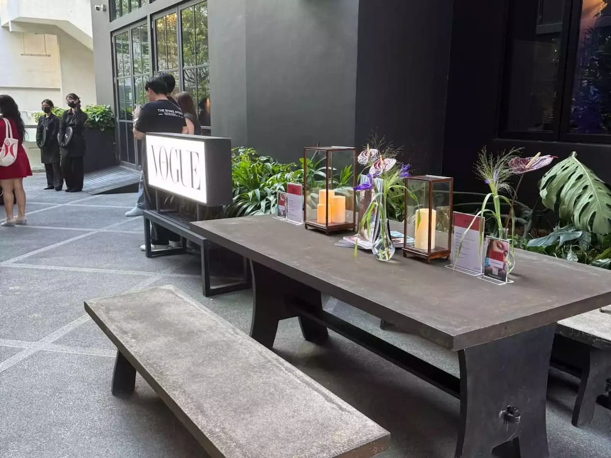 Outdoor event table with décor, candles, and illuminated Vogue sign.