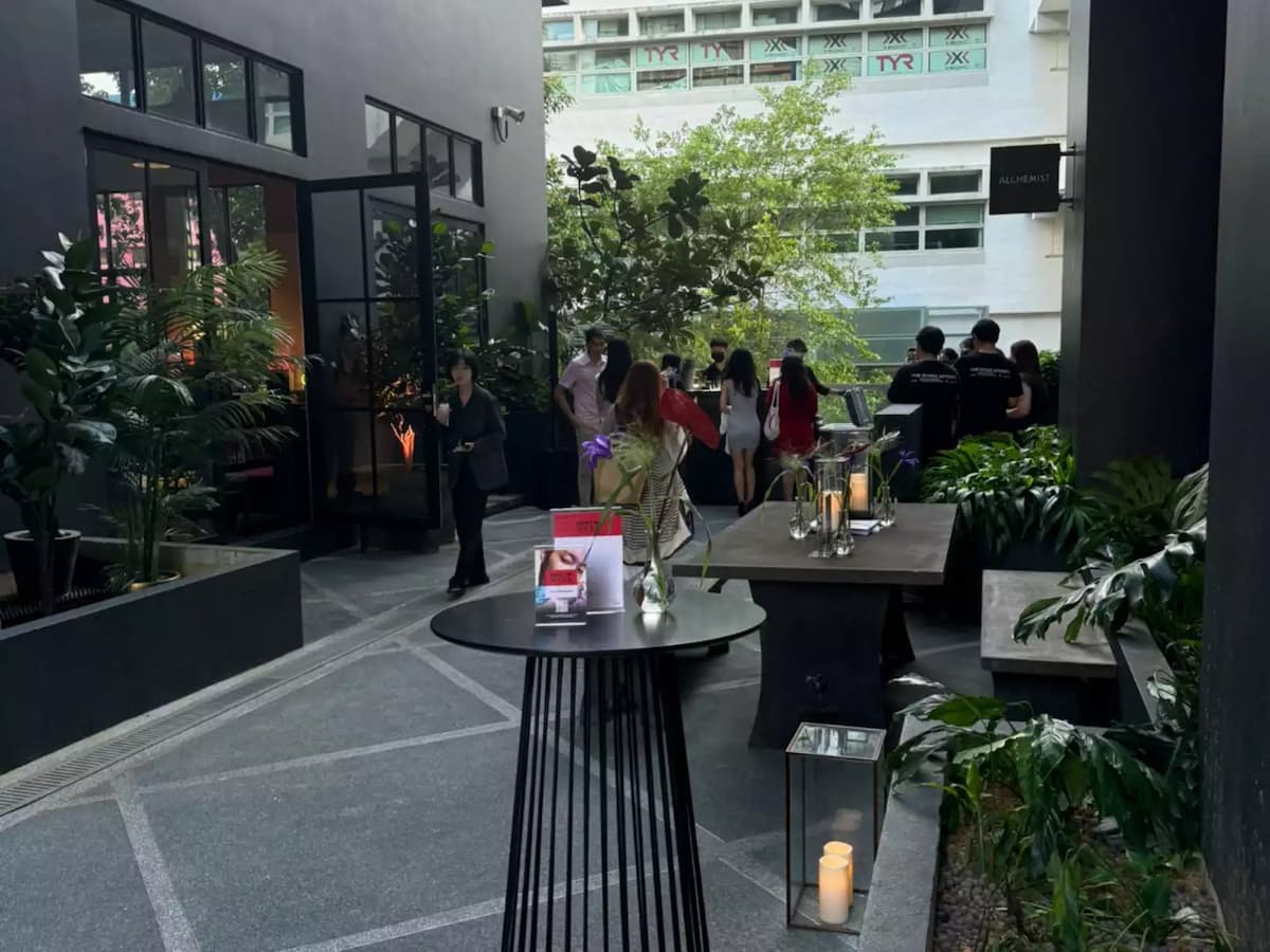 Outdoor courtyard event with cocktail tables, greenery, and guests mingling.
