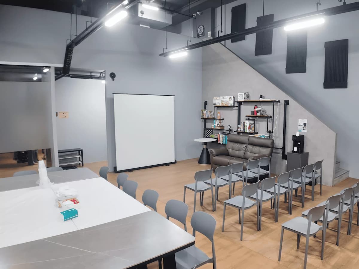 Flexible event room with classroom seating, projector screen, lounge sofa, and a casual, modern setup.