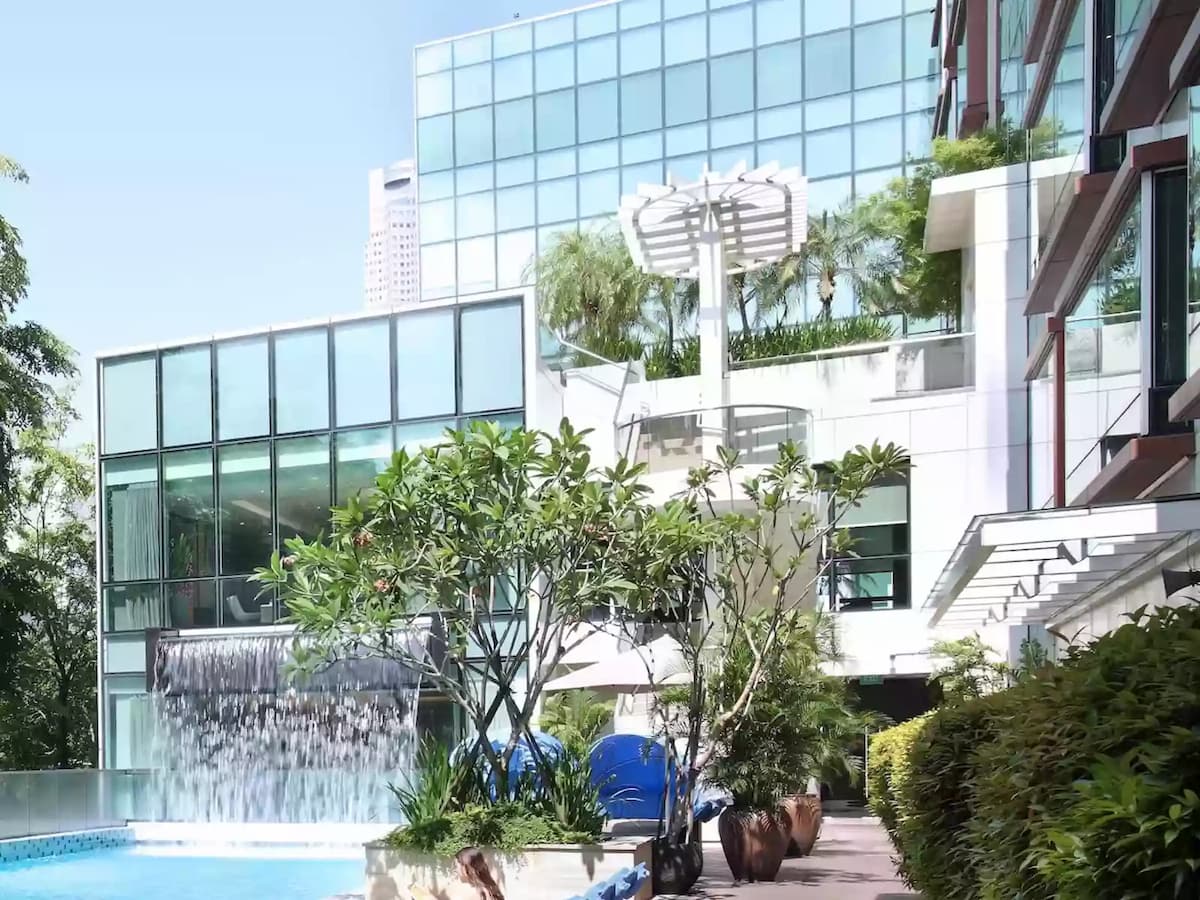 Hotel pool area with waterfall feature and modern architecture.