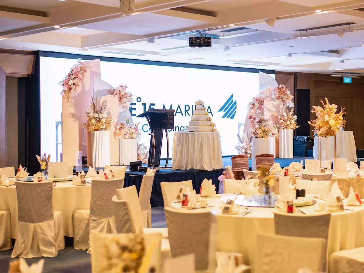 Wedding banquet setup with stage, cake display, and floral décor