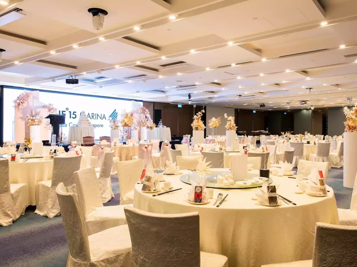 Grand wedding banquet hall with round tables and elegant floral centerpieces.