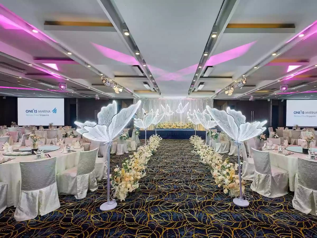 Wedding banquet hall with illuminated aisle décor and elegant table settings.