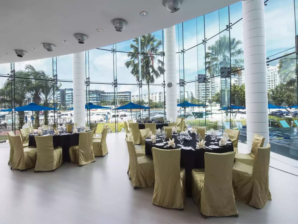 Elegant banquet setup with round tables, gold chairs, and marina views.