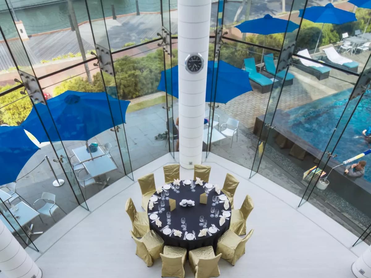 Round dining table setup with gold chairs overlooking waterfront patio.