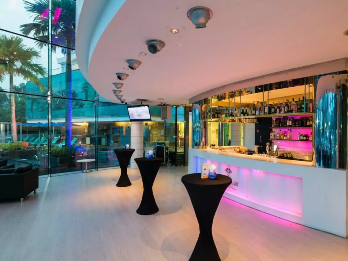 Modern event bar with illuminated counter, cocktail tables, and glass walls.