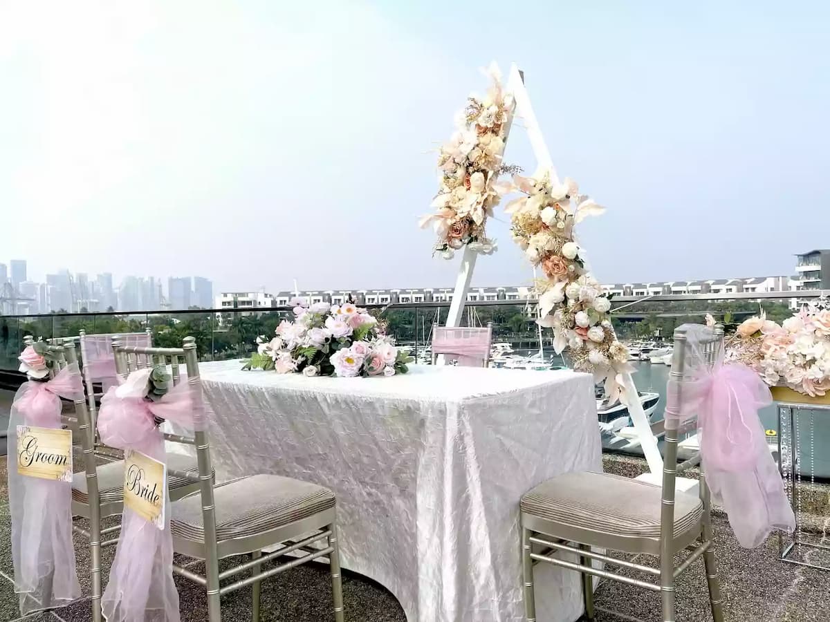 Outdoor wedding signing table with floral arch and pink décor.