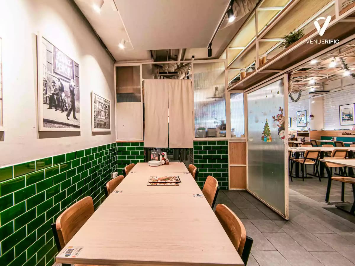 Private dining table with wooden seating, green tiled walls, framed vintage photos, and soft ambient lighting.