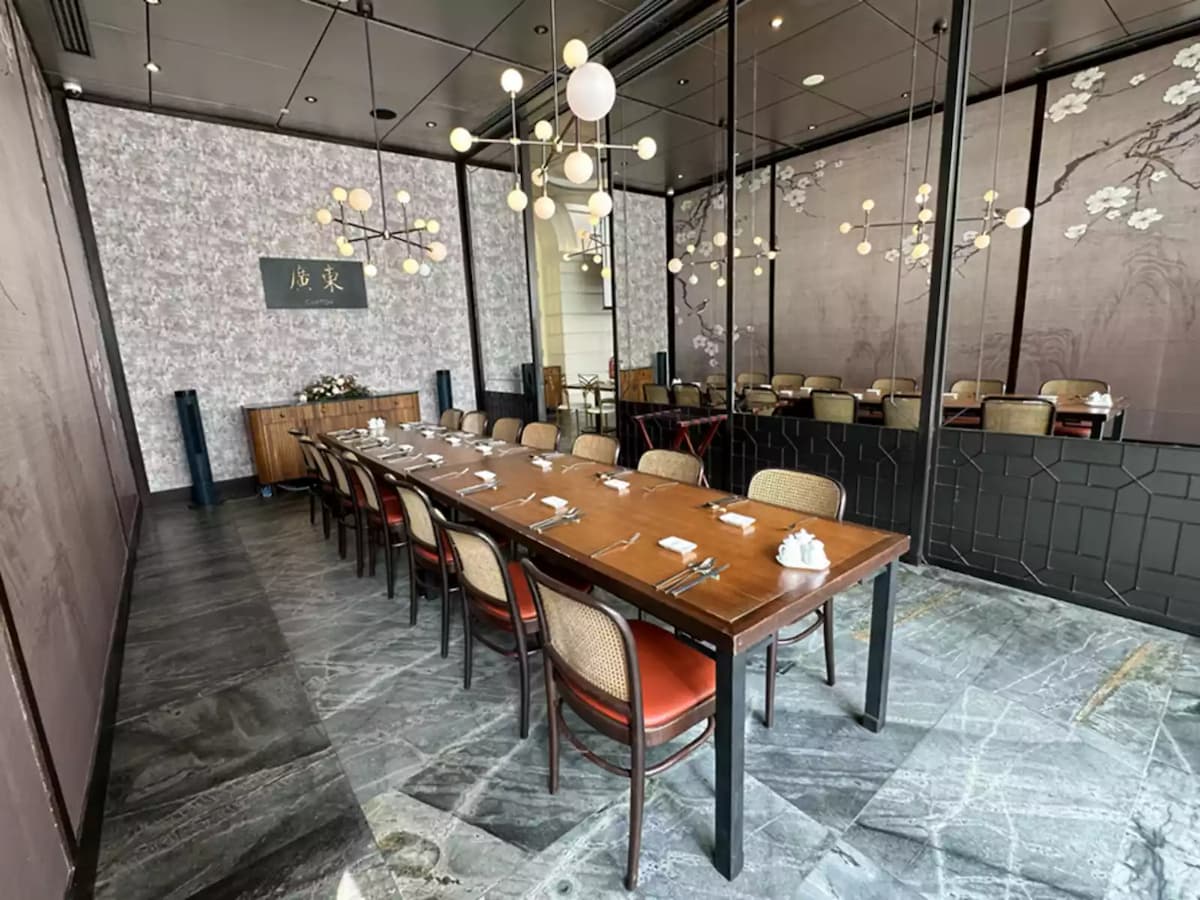 Private dining room with long table, mirrored walls, and pendant lights.