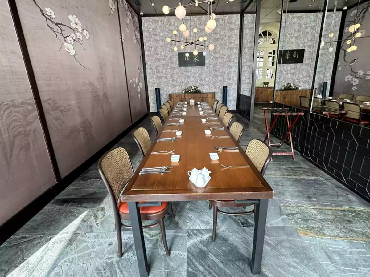 Private dining room with long table, mirrored wall, and pendant lights