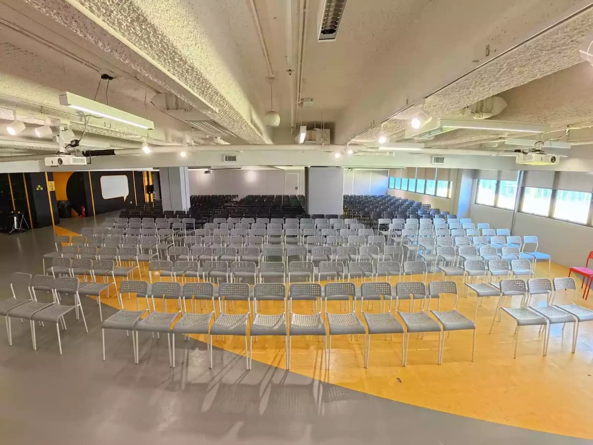 Large event hall with rows of chairs, projector setup, and wide windows for natural light.
