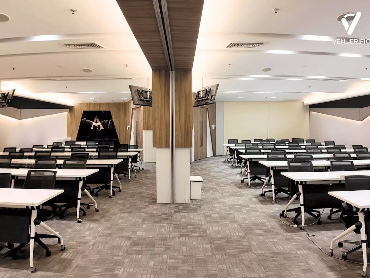 Mutiara Event Space with dual classroom-style rooms, long tables, ergonomic chairs, and a central partition for flexible event setups