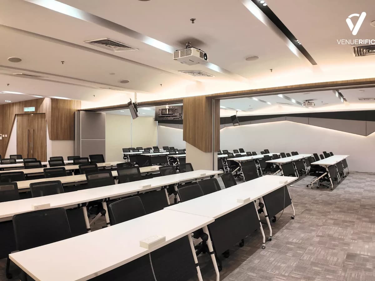 Mutiara Event Space featuring a flexible classroom-style layout with long tables, ergonomic chairs, ceiling-mounted projector, and partitioned rooms