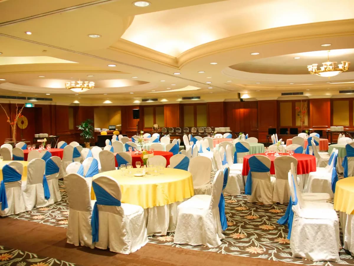 Elegant ballroom banquet setup with round dining tables, chair sashes, and warm chandelier lighting—ideal for weddings, gala dinners, corporate banquets, and formal celebrations.