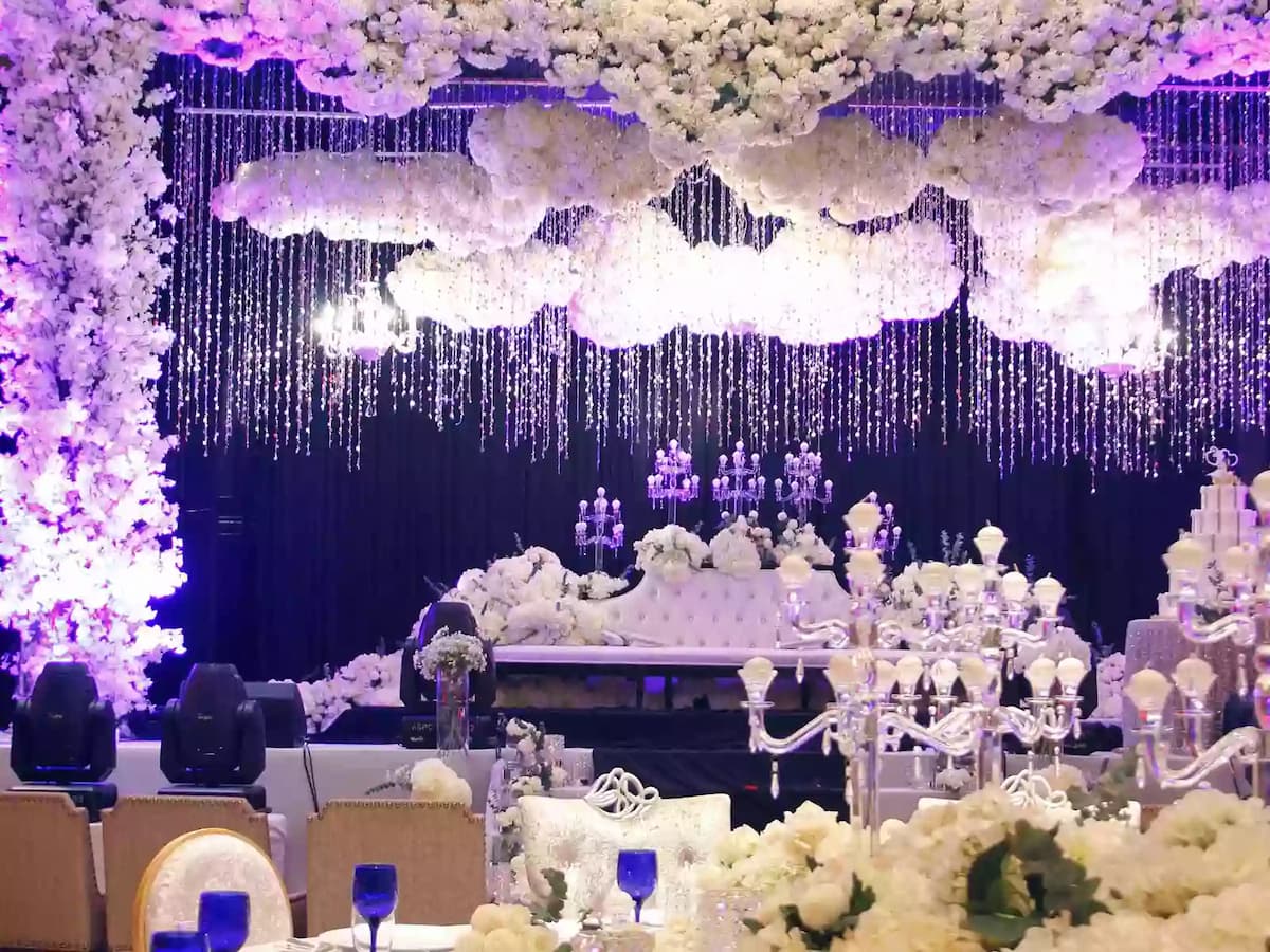 Luxurious wedding stage setup adorned with cascading florals, crystal chandeliers, and elegant décor