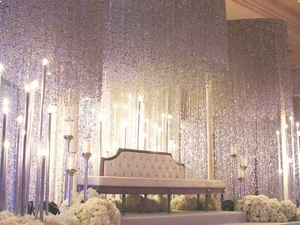 Luxurious wedding stage adorned with shimmering crystal backdrops, tall candle stands, and elegant floral arrangements—perfect for grand wedding receptions, engagements, and upscale celebration events.