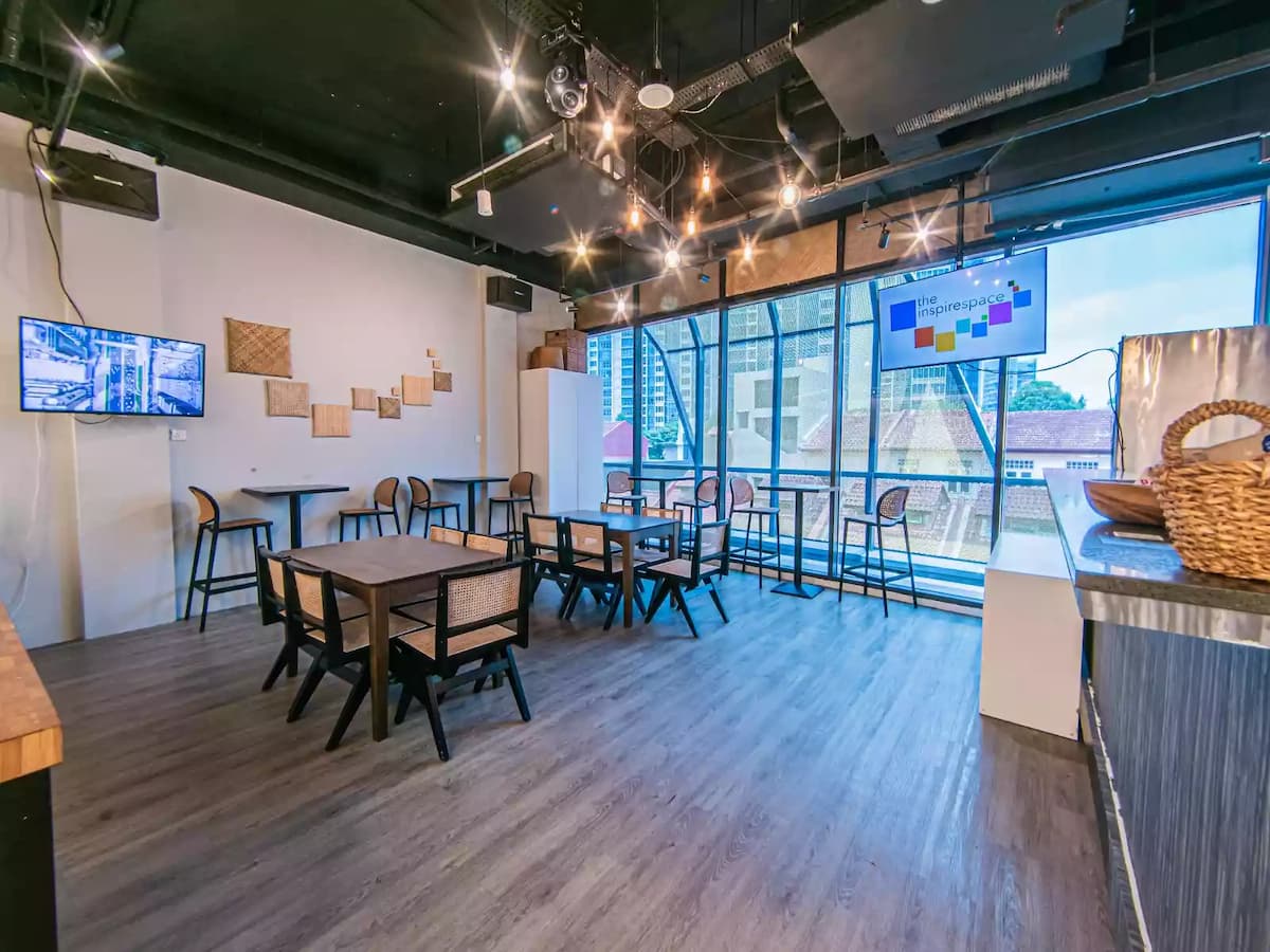 Contemporary workshop and event space with flexible table seating, large windows, and presentation screens—ideal for meetings, workshops, networking sessions, and small corporate events.