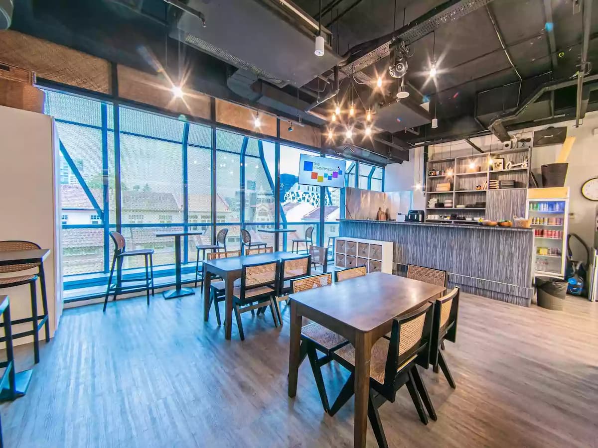 Contemporary workshop and event space with flexible table seating, large windows, and presentation screens—ideal for meetings, workshops, networking sessions, and small corporate events.